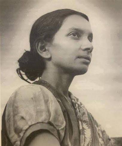 Archival black-and-white photograph of Kalpana Datta in a patterned sari, looking upward and slightly to her right, photographed outdoors against an open sky.